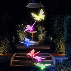 colorful lights in the shape of butterflies are hanging from a fountain at night time,