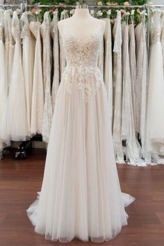 a wedding dress is displayed in front of a rack of gowns and dresses on display