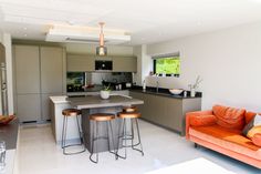 an orange couch sitting in the middle of a living room next to a kitchen island