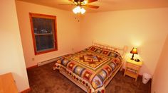 a bed room with a neatly made bed and a ceiling fan