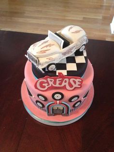 a three tiered cake decorated with cars and the words grease on it's side