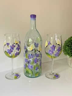 three wine glasses and a bottle with flowers painted on them