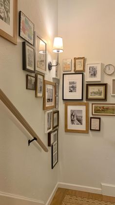 there are many framed pictures on the wall next to the banister and stair case