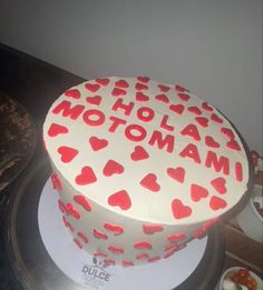 a white cake with red hearts and the words motoman on it is sitting on a table