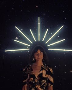 a woman standing in front of a star filled sky with bright lights on her face