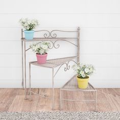 two potted plants are sitting on a metal shelf next to a white painted wall