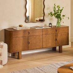 a wooden dresser sitting next to a mirror on top of a wall in a living room