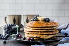 a stack of pancakes on a plate with blueberries and bananas next to the pan