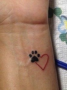 a dog paw and heart tattoo on the wrist