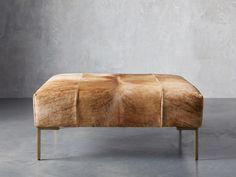 a bench made out of wood and fur on top of a cement floor in front of a concrete wall