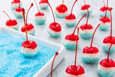 blue and white desserts with red cherries on them are ready to be eaten