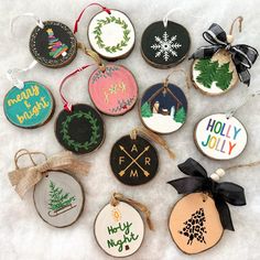 twelve decorated christmas ornaments are arranged on the snow covered ground, with ribbons and tags hanging from each ornament