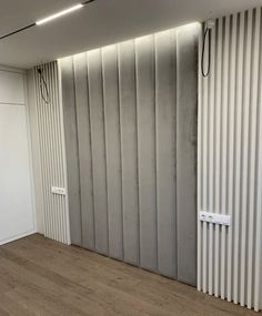 an empty room with white walls and wooden flooring in the center, next to a radiator