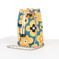 a blue and yellow flowered purse on a white surface with a chain attached to it