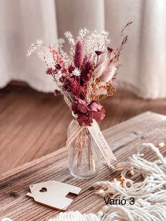 a vase filled with lots of flowers on top of a wooden table next to a tag