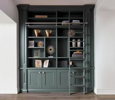 a green bookcase with books and vases on it