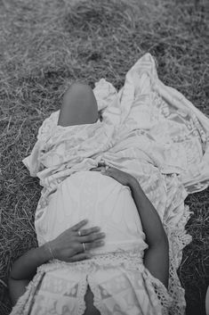 a woman laying on the ground wrapped in a blanket with her hand over her stomach