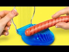 two hands are playing with a toy string instrument and a hot dog on the strings