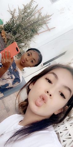 two young women taking a selfie with their cell phones