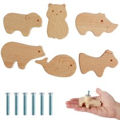 a hand holding some wooden animals and screws on a white background with other wood pieces