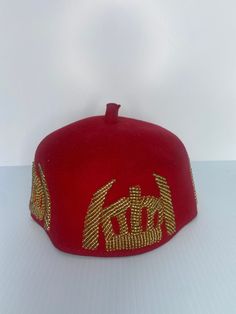 Our magnificent Igwe Odogwu African Chieftaincy Igbo Ozo Cap will elevate your look while also honouring tradition. Crafted with painstaking attention to detail, this African men's velvet cap studded with beads represents Nigerian monarchy and cultural pride. Whether it's for a special occasion like a traditional wedding or just to add a bit of elegance to your outfit, our Nigerian distinctive traditional men's cap reflects your heritage and refinement. The bold red colour of the Igwe hat represents leadership and power, making it a statement piece that draws attention. This chieftaincy cap, handcrafted from premium materials such as velvet fabric and traditional Igbo wax, showcases elaborate designs inspired by Igbo cultural elements, including an iconic tusk design. It's not only a hat; Red Adjustable Hat With Round Crown, Red Adjustable Hat, Adjustable Round Crown Hats For Celebration, Red Adjustable Round Crown Hat, Adjustable Mini Cap Hats For Church, Adjustable High Crown Gold Hat, Ceremonial Costume Hat With Structured Crown, Adjustable Ceremonial Costume Hat With Structured Crown, Traditional Adjustable Snapback Hat