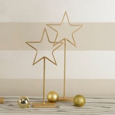 three gold ornaments are placed next to each other in front of a white striped wall