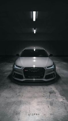 the front end of a white car in a dark garage