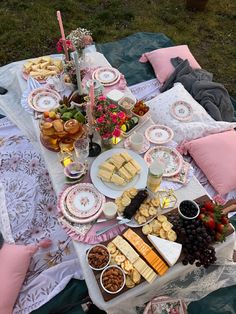 an outdoor picnic with food and drinks on the table, including cheeses, crackers