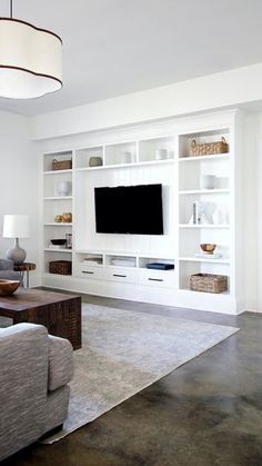 a living room filled with furniture and a flat screen tv mounted on a wall unit