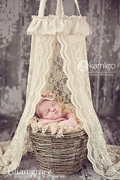 a baby is laying in a basket with a canopy over it's head and has her eyes closed