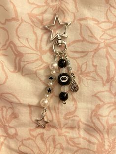 a key chain with beads and charms hanging from it's side on a bed