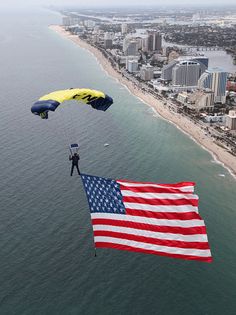 two people parasailing over the ocean with an american flag in front of them