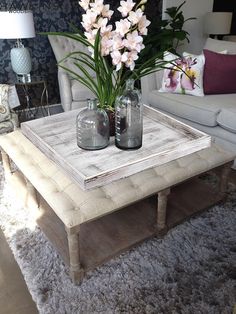 two vases with flowers are sitting on a coffee table