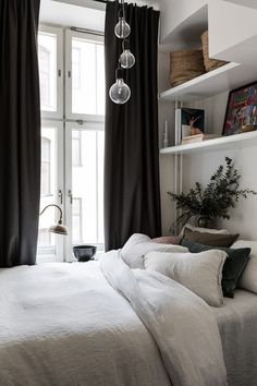 a bedroom with black curtains and white bedding