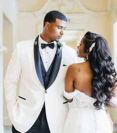 a man in a tuxedo standing next to a woman