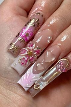 a woman's hand with pink and gold nail polishes on her nails, decorated with flowers