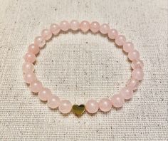 "This sweet little bracelet uses 6mm Rose Quartz beads & you can choose between a gold, silver, or black heart.  This bracelet is made to order. When selecting your size, measure your wrist at the smallest point & then add 1/4\"-1/2\" for comfort. Please message me if you need any customizations. :-)  Listing is for one bracelet." Minimalist Heart Beaded Bracelets As Gift, Heart-shaped Stretch Bracelet With 8mm Beads As Gift, Heart-shaped Bracelet With 8mm Beads As Gift, Heart Shaped 8mm Beads Bracelet As Gift, Heart Shaped 8mm Beads Bracelet Gift, Heart-shaped Bracelet With 8mm Beads For Gift, Elegant Rose Gold Heart Beaded Bracelets, Rose Gold Beaded Bracelets With Heart Charm As Gift, Dainty Round Beads Bracelets For Valentine's Day