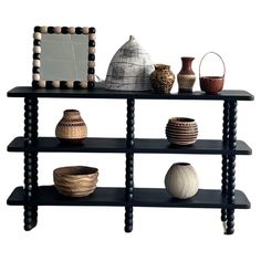 a black shelf with vases and other decorative items on it, along with a mirror