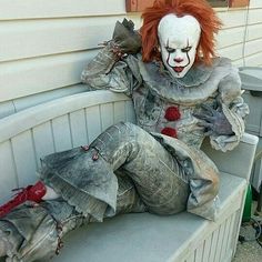 a creepy clown sitting on top of a bench