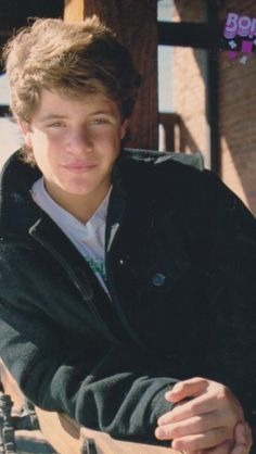 a young man is sitting in front of a giant chess board and posing for the camera