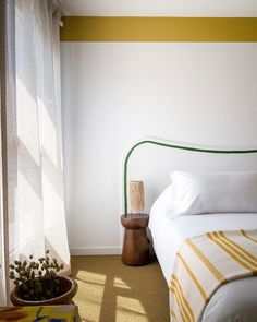 a bed sitting next to a window in a room with yellow and white stripes on the walls