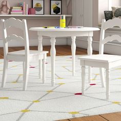 a white table and two chairs in a room with a rug on the floor next to it