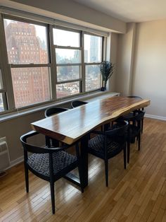 a dining room table and chairs in front of a large window overlooking the cityscape