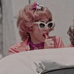 two women with sunglasses on their heads are looking at each other and one is brushing her teeth