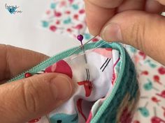 someone is stitching together fabric with a sewing needle in their hand and the thread has been sewn on