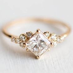 a gold engagement ring with a princess cut diamond surrounded by small white and clear stones