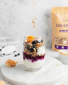 an image of granola in a glass with blueberries and oranges on the side