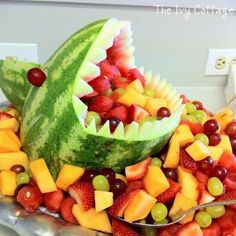 a watermelon shark made out of fruit on a platter