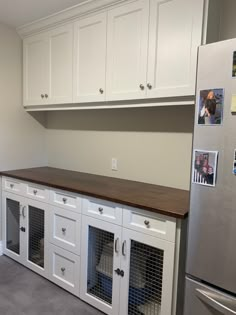 a kitchen with white cabinets and dog kennels on the counter top, in front of a stainless steel refrigerator