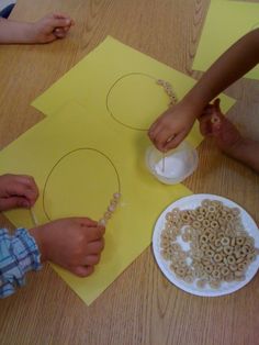 two children are making necklaces out of cereal krispy kreme treats on the table